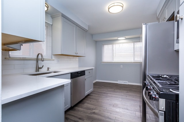 kitchen featuring visible vents, dark wood finished floors, stainless steel appliances, light countertops, and a sink