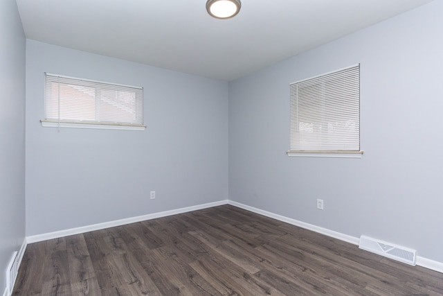 spare room featuring dark wood finished floors, visible vents, and baseboards