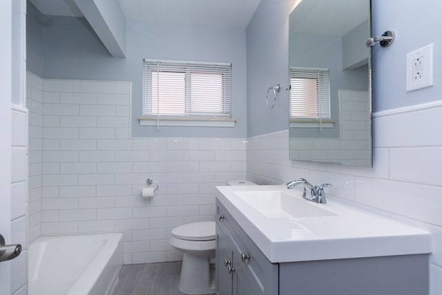 full bathroom featuring a tub to relax in, vanity, toilet, and tile walls