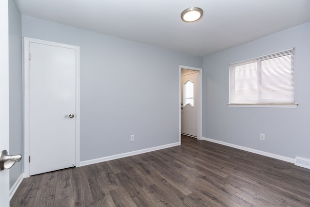 unfurnished room featuring visible vents, baseboards, and dark wood-style flooring