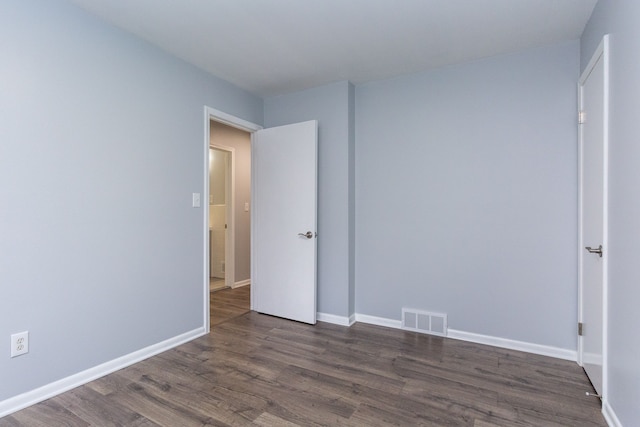 spare room featuring visible vents, dark wood finished floors, and baseboards