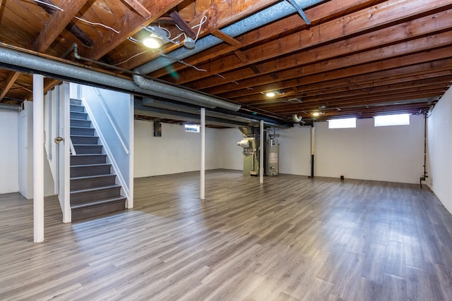 below grade area featuring gas water heater, stairway, and wood finished floors