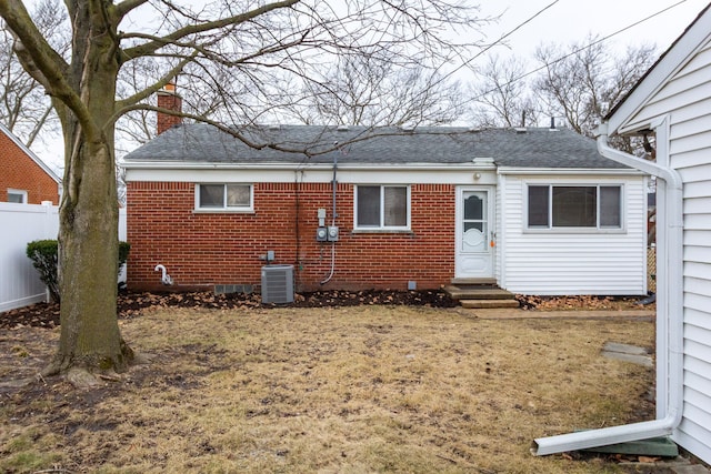 view of front of home with entry steps, a chimney, fence, central AC, and brick siding