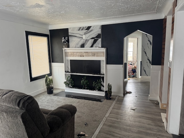 living room with a wainscoted wall, a textured ceiling, a decorative wall, and wood finished floors