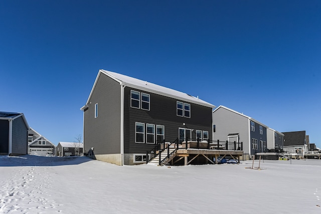 snow covered back of property featuring a deck and stairway