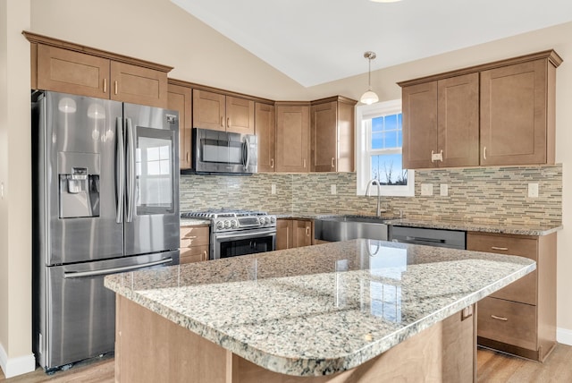 kitchen featuring vaulted ceiling, decorative backsplash, light wood-style floors, stainless steel appliances, and a sink