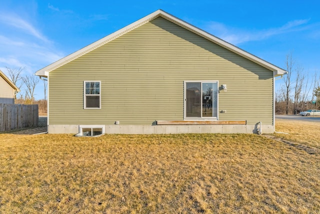 rear view of house featuring fence and a lawn