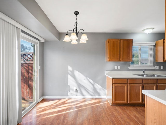 kitchen featuring brown cabinets, light countertops, a sink, and light wood-style flooring