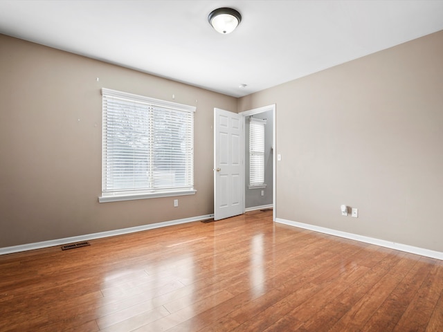 empty room featuring visible vents, baseboards, and wood finished floors