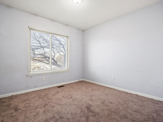 spare room featuring carpet floors, visible vents, and baseboards