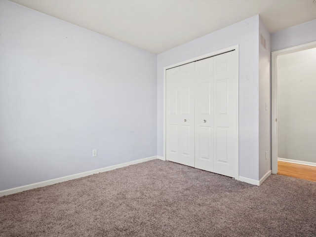 unfurnished bedroom with a closet, carpet flooring, and baseboards