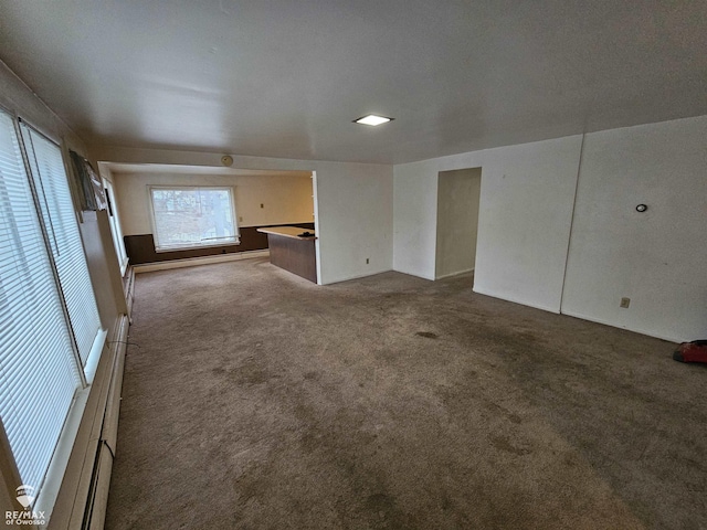 unfurnished living room with baseboard heating and carpet flooring