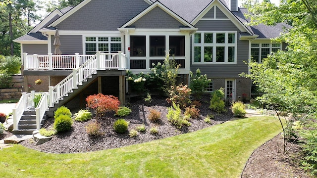 back of house featuring a yard, a chimney, a sunroom, a deck, and stairs