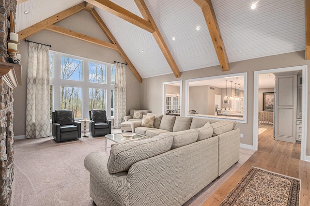 living area with light wood finished floors, baseboards, beamed ceiling, a fireplace, and high vaulted ceiling