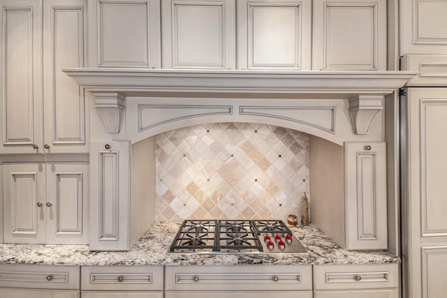 kitchen featuring stainless steel gas cooktop, cream cabinets, backsplash, and light stone countertops