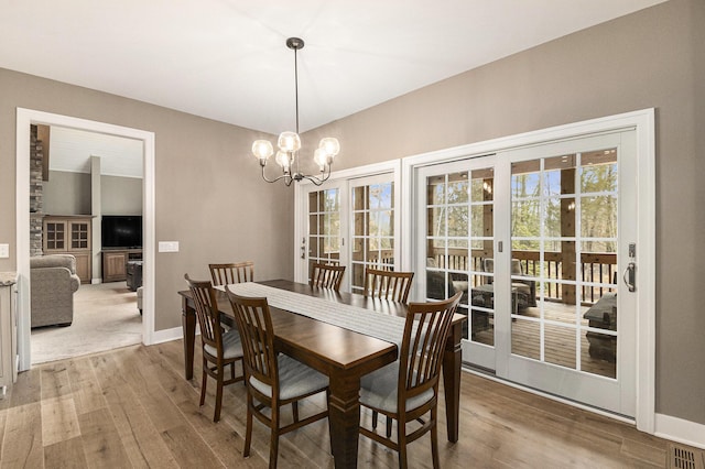 dining room featuring an inviting chandelier, visible vents, baseboards, and wood finished floors