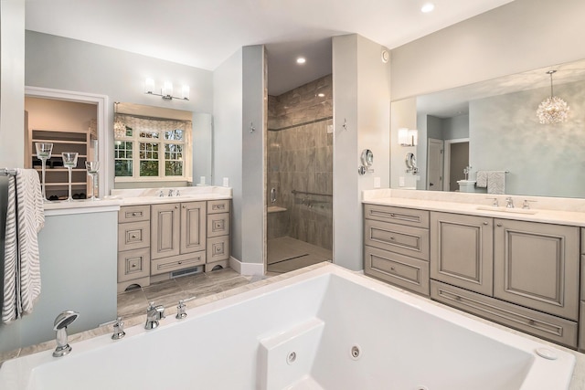 bathroom with a jetted tub, a stall shower, two vanities, and a sink