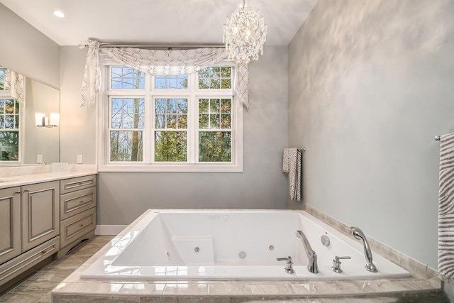 full bathroom with a chandelier, baseboards, vanity, and a tub with jets