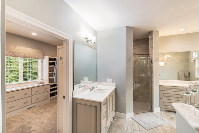 full bath featuring two vanities, a sink, marble finish floor, a stall shower, and a walk in closet