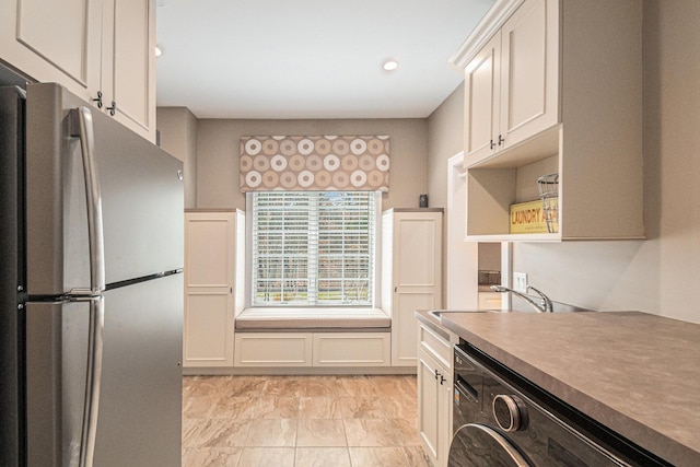 kitchen with a sink, white cabinetry, marble finish floor, freestanding refrigerator, and washer / clothes dryer