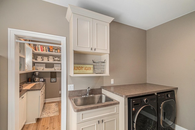 clothes washing area with light wood-type flooring, cabinet space, separate washer and dryer, and a sink