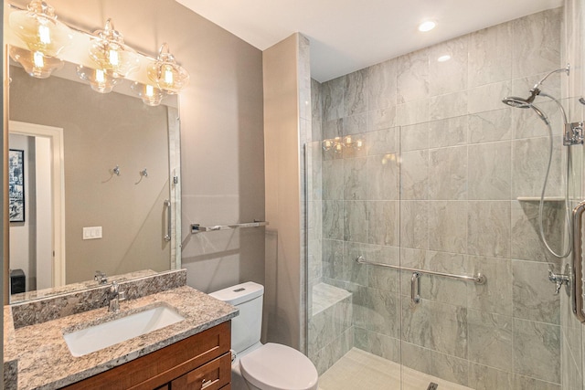 bathroom with toilet, a shower stall, and vanity