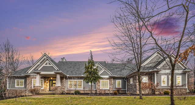 view of front of house with a front yard, stone siding, and a chimney
