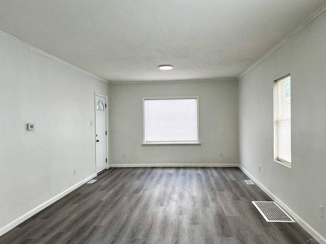 empty room featuring visible vents, crown molding, and baseboards