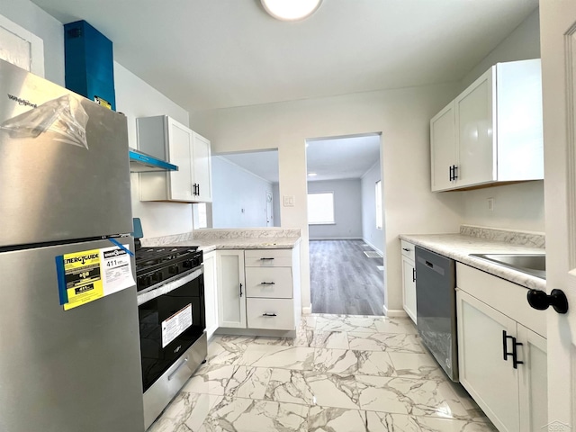 kitchen with marble finish floor, appliances with stainless steel finishes, a sink, and light countertops