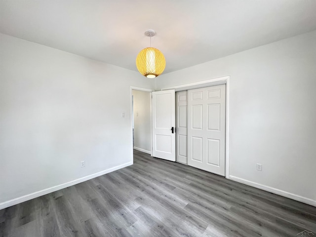 unfurnished bedroom featuring baseboards, dark wood finished floors, and a closet