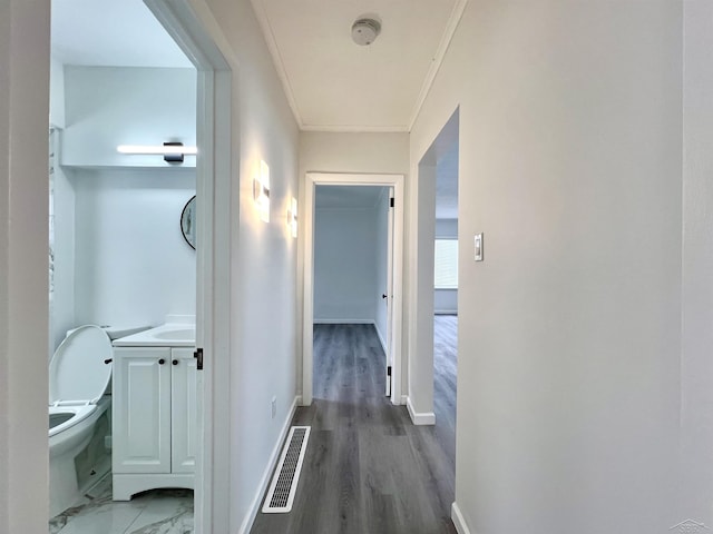 hall with ornamental molding, wood finished floors, visible vents, and baseboards