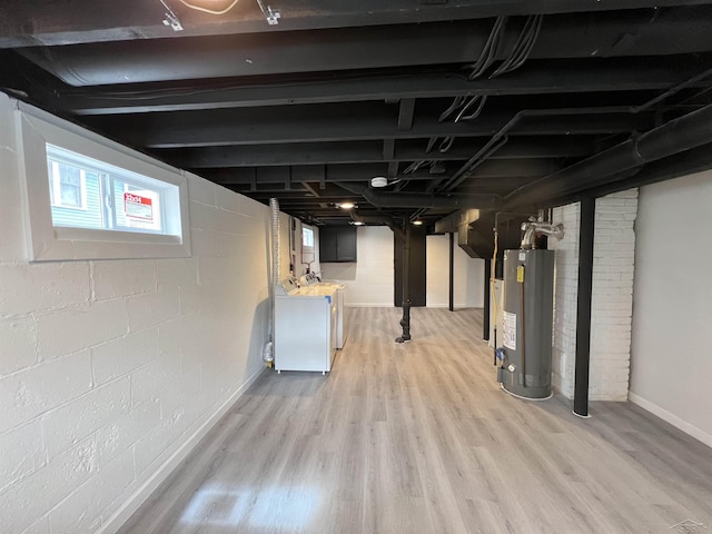 below grade area with light wood-type flooring, gas water heater, and washing machine and dryer