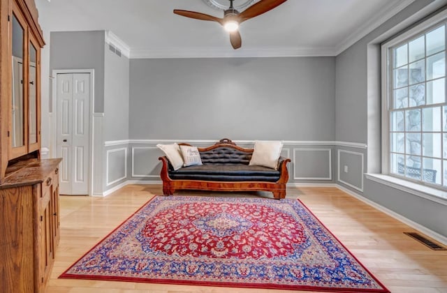 living area with visible vents, light wood-type flooring, and crown molding