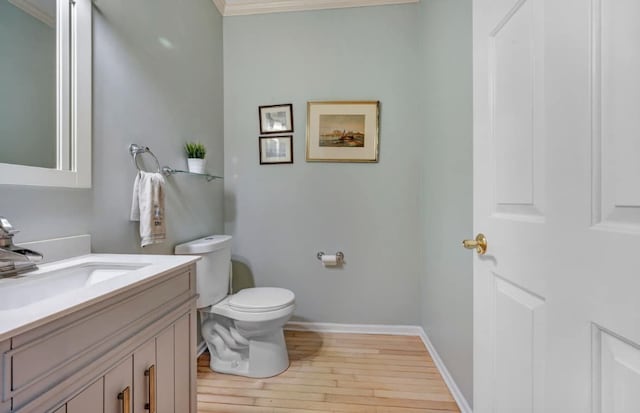 bathroom featuring baseboards, toilet, wood finished floors, and vanity