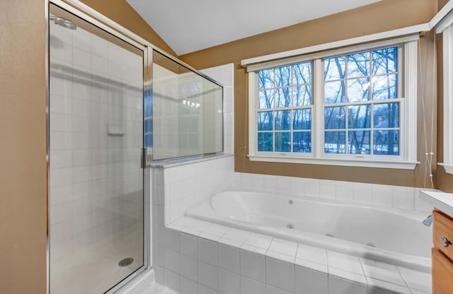 bathroom featuring a stall shower, vanity, lofted ceiling, and a whirlpool tub