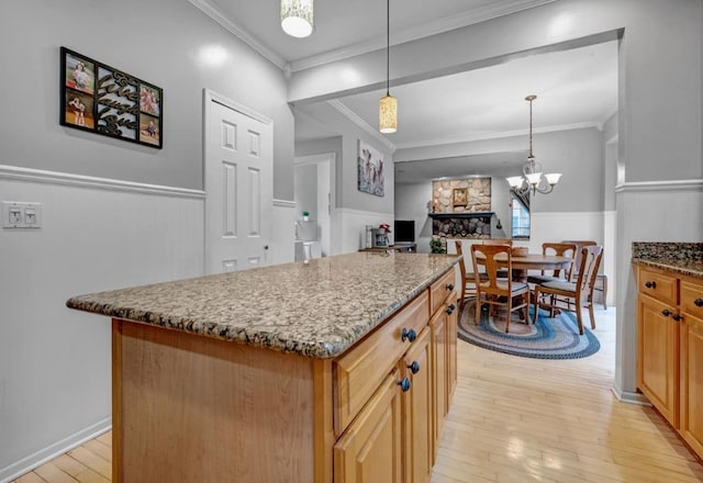 kitchen featuring ornamental molding, light wood-type flooring, stone counters, and wainscoting