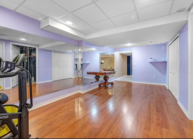 workout area featuring a drop ceiling, baseboards, and wood finished floors