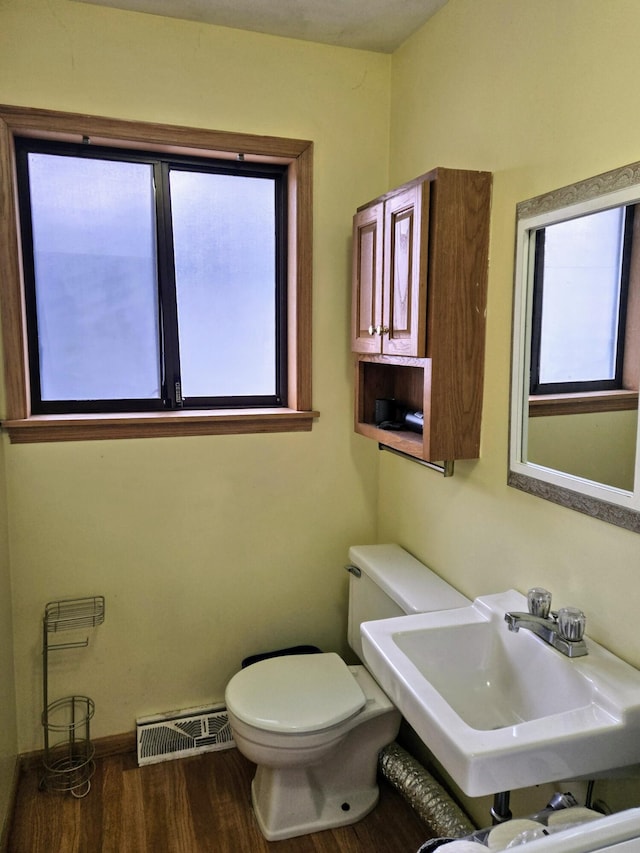 half bathroom with toilet, visible vents, a sink, and wood finished floors