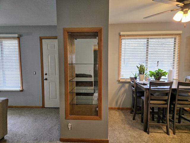 carpeted dining room with ceiling fan and baseboards