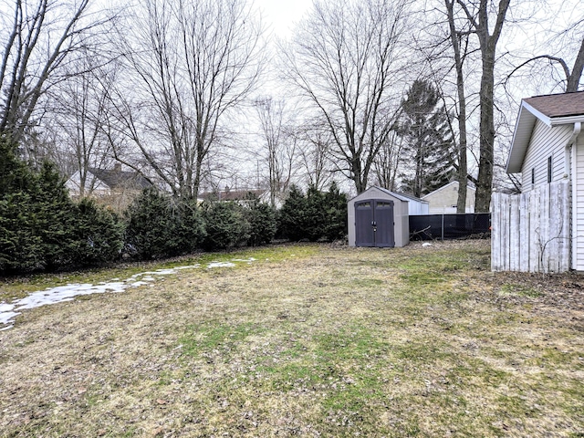 view of yard featuring a storage shed, fence, and an outbuilding