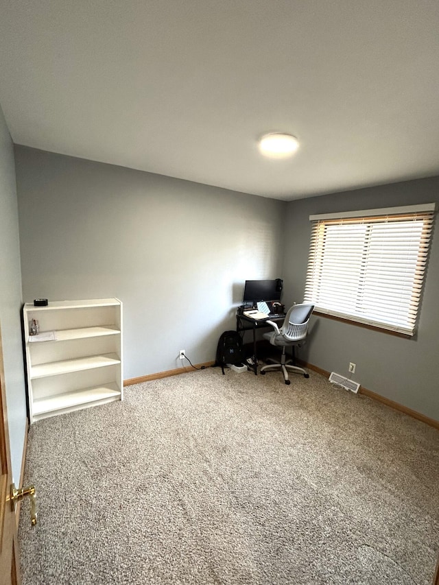 unfurnished office with carpet, visible vents, and baseboards