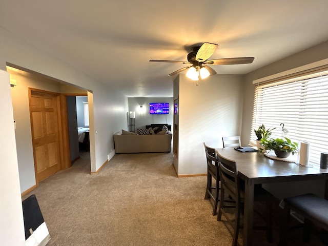 dining area with ceiling fan, baseboards, and light colored carpet