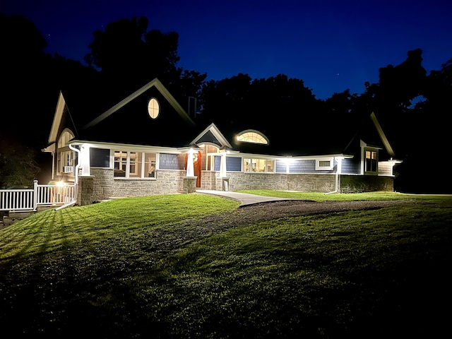 view of front facade featuring stone siding and a lawn