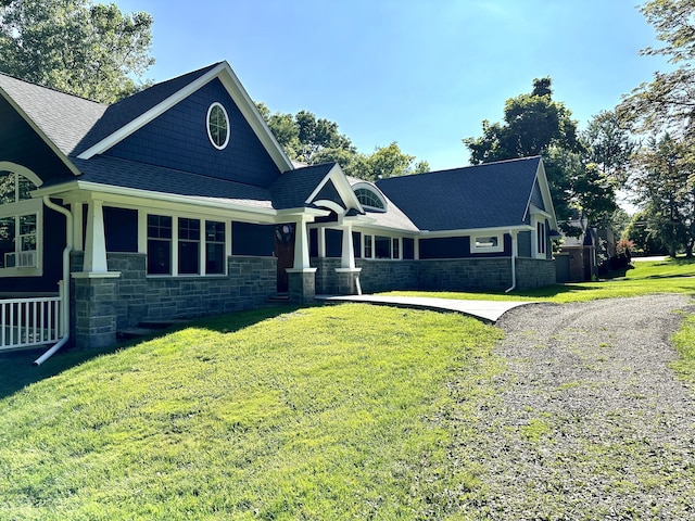 view of front facade with driveway, a front lawn, and stone siding