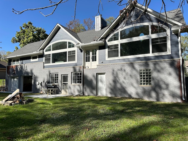 back of house with a patio area, brick siding, a yard, and a chimney