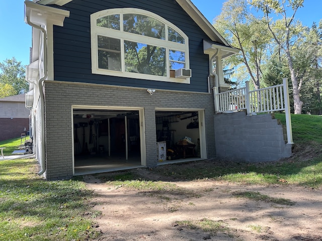 rear view of property featuring brick siding, driveway, and an attached garage