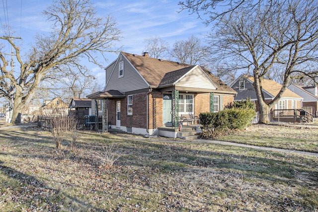 view of front of property with fence, a front lawn, and brick siding