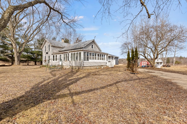 view of front facade with a sunroom and a chimney