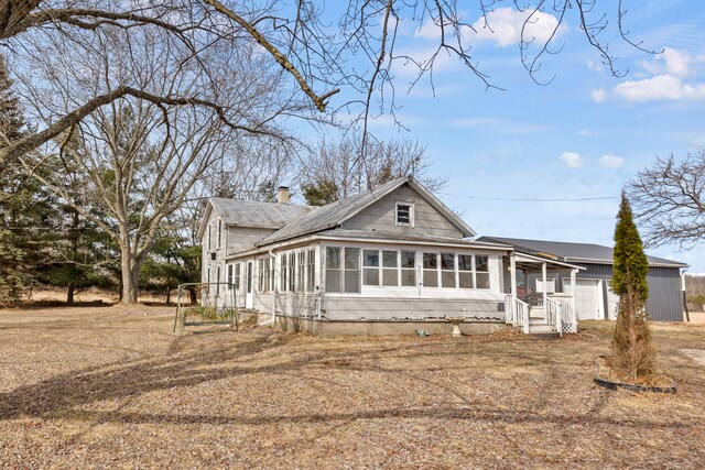 view of front of home with a chimney, an attached garage, and a sunroom