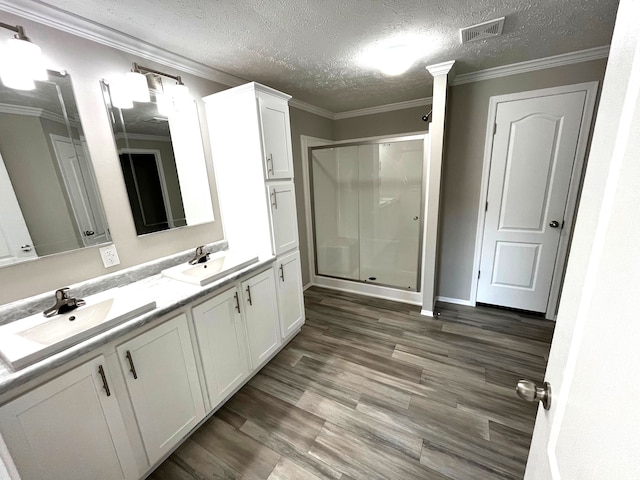 bathroom with visible vents, a shower stall, ornamental molding, and a sink